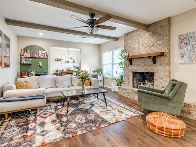 living area featuring visible vents, beam ceiling, a ceiling fan, wood finished floors, and a fireplace