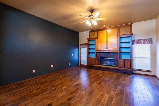 unfurnished living room with dark wood finished floors, a fireplace, baseboards, and ceiling fan