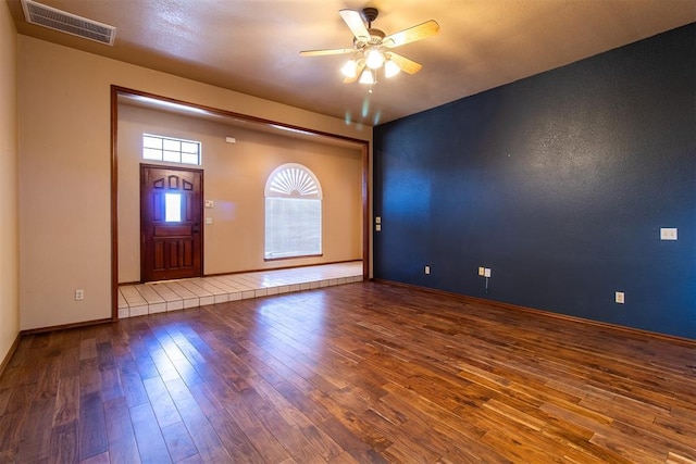 spare room featuring hardwood / wood-style floors, baseboards, visible vents, and ceiling fan