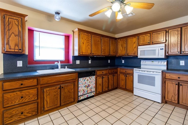 kitchen featuring dark countertops, brown cabinets, white appliances, and a sink