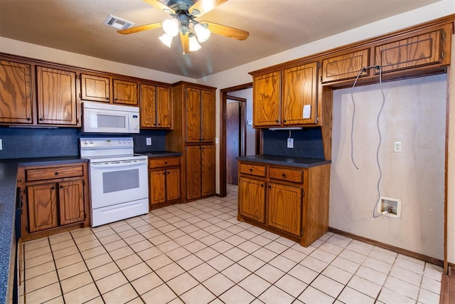 kitchen featuring white appliances, dark countertops, brown cabinets, and ceiling fan