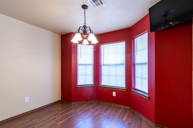 unfurnished room with visible vents, an inviting chandelier, and wood finished floors