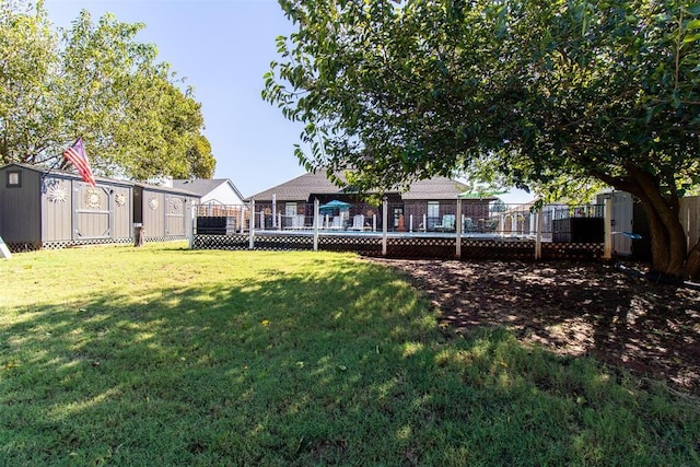 view of yard featuring a wooden deck, a storage shed, an outdoor structure, and fence