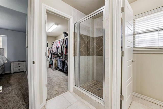 bathroom featuring tile patterned flooring, a shower stall, a spacious closet, and ensuite bath