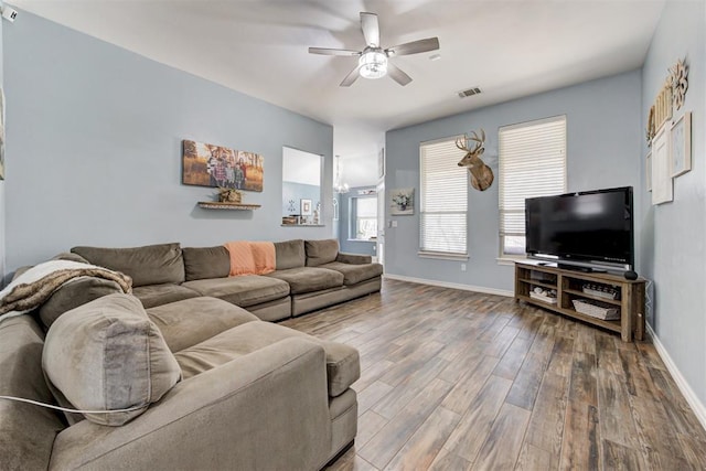 living room featuring visible vents, a ceiling fan, baseboards, and wood finished floors