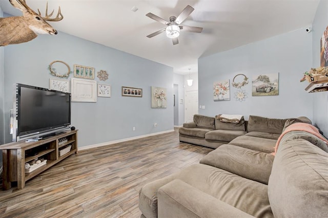 living room featuring baseboards, ceiling fan, and wood finished floors