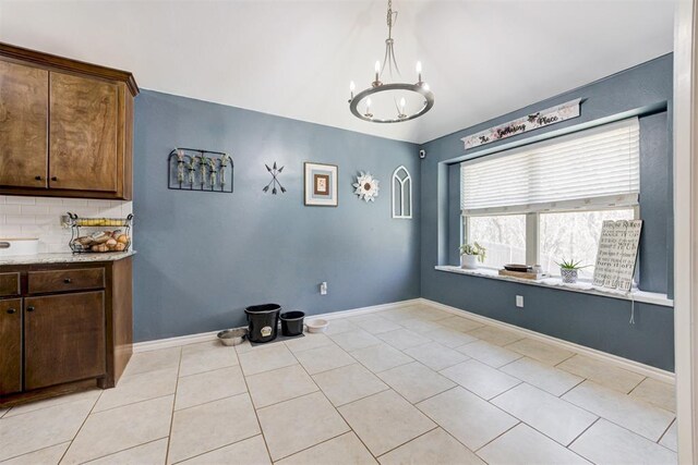dining room featuring baseboards, an inviting chandelier, light tile patterned floors, and lofted ceiling