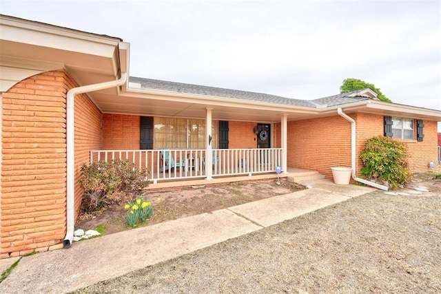 property entrance featuring brick siding and covered porch