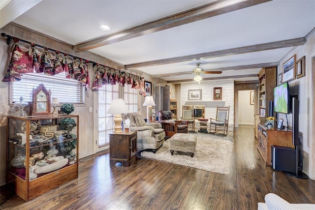 living room with visible vents, beam ceiling, ceiling fan, dark wood-type flooring, and a large fireplace