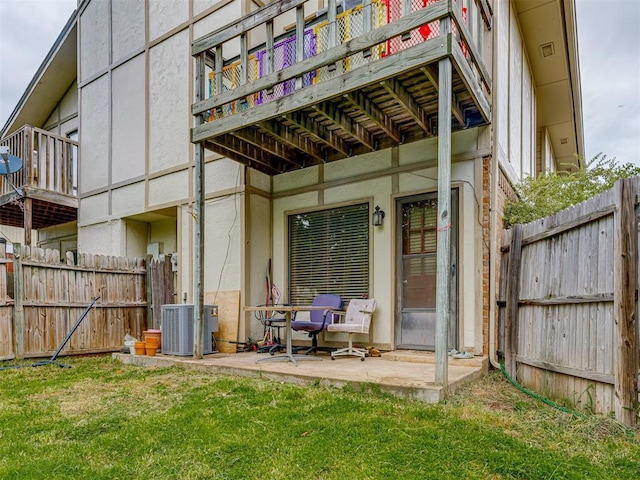 back of property featuring stucco siding, a lawn, cooling unit, and fence