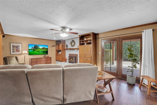 living room featuring ceiling fan, a textured ceiling, dark wood finished floors, and ornamental molding