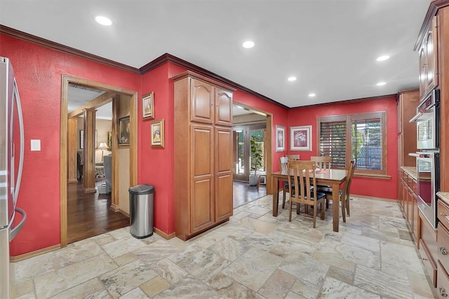 dining room with a wealth of natural light, recessed lighting, stone tile flooring, and crown molding