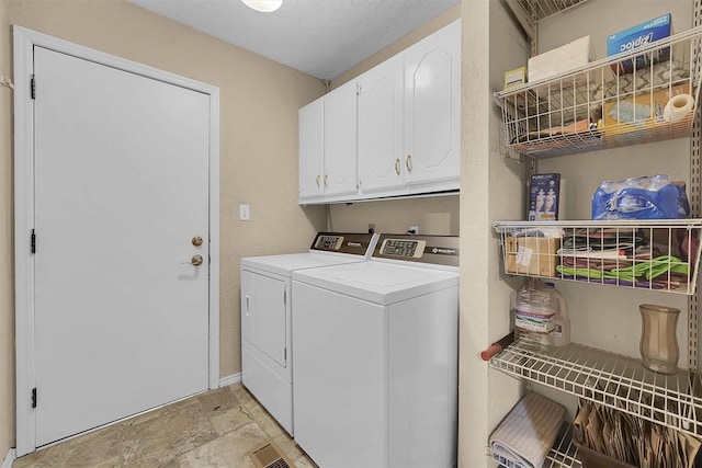 laundry room featuring stone finish flooring, cabinet space, baseboards, and washing machine and clothes dryer