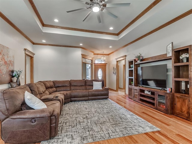 living area with a raised ceiling, recessed lighting, a ceiling fan, and light wood finished floors