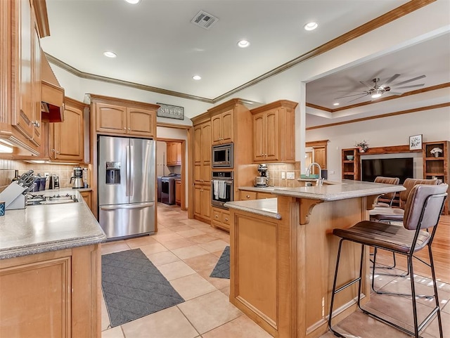 kitchen with visible vents, a breakfast bar, open floor plan, a peninsula, and appliances with stainless steel finishes