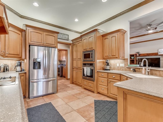 kitchen with a sink, crown molding, and stainless steel appliances