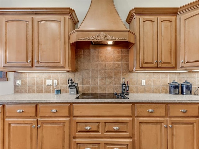 kitchen featuring custom exhaust hood, black electric stovetop, light countertops, and tasteful backsplash