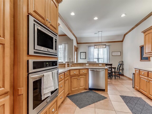 kitchen with a peninsula, stainless steel appliances, crown molding, and a sink