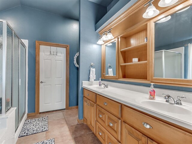 full bathroom featuring tile patterned flooring, double vanity, a stall shower, and a sink