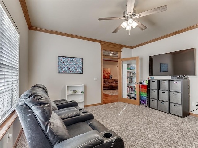 carpeted living room featuring baseboards, ornamental molding, and a ceiling fan