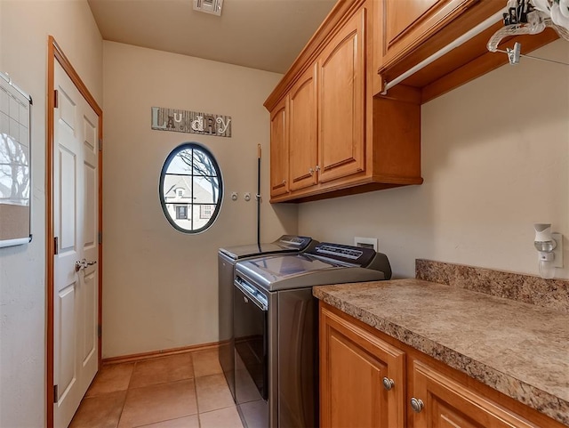 washroom featuring visible vents, cabinet space, light tile patterned floors, baseboards, and washing machine and clothes dryer