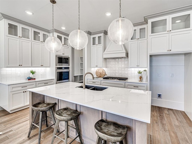 kitchen featuring a sink, appliances with stainless steel finishes, light wood-style flooring, and pendant lighting