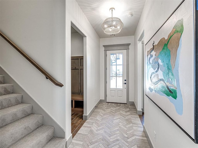 entrance foyer featuring an inviting chandelier, stairway, and baseboards