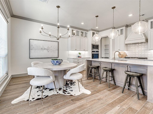 dining space featuring visible vents, baseboards, light wood-style floors, and ornamental molding