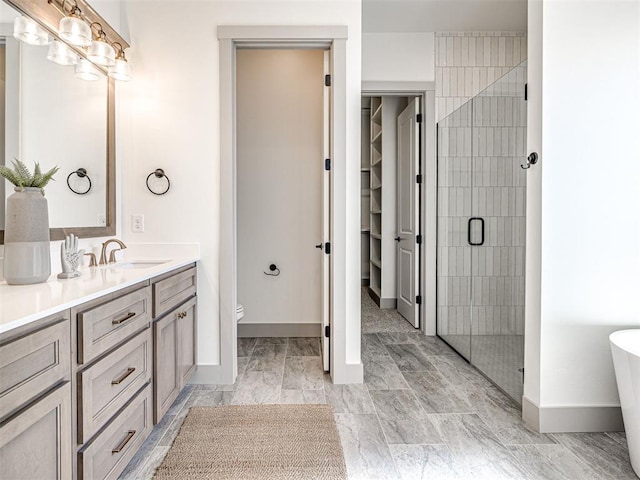 full bathroom featuring vanity, baseboards, a soaking tub, a stall shower, and toilet