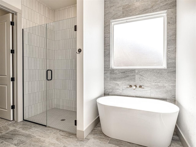 bathroom with baseboards, a freestanding bath, and a stall shower