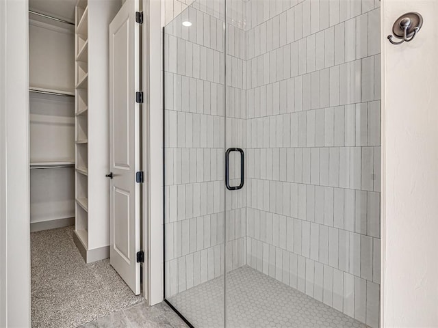 full bathroom featuring a stall shower, a walk in closet, and baseboards