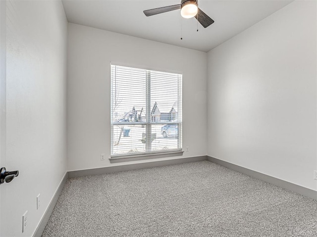 carpeted empty room with a ceiling fan and baseboards