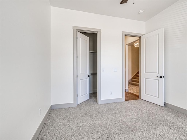 unfurnished bedroom featuring a spacious closet, a closet, baseboards, and carpet