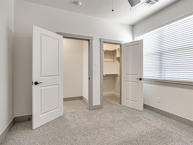 unfurnished bedroom featuring visible vents, a closet, baseboards, light colored carpet, and a spacious closet