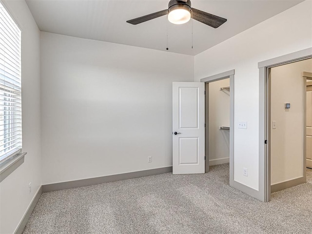 unfurnished bedroom with a closet, a walk in closet, baseboards, and carpet floors