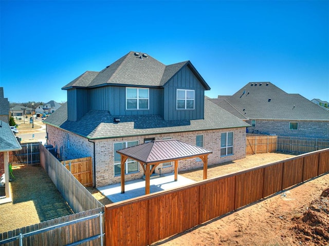 rear view of property with a gazebo, a fenced backyard, a patio area, and brick siding