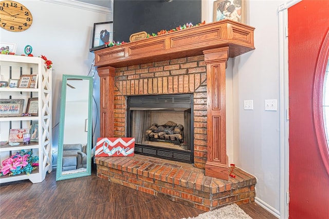 interior details with a brick fireplace, crown molding, baseboards, and wood finished floors