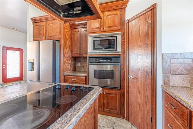 kitchen with backsplash, stainless steel appliances, and brown cabinets