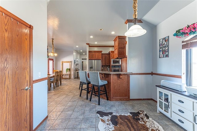 kitchen with a kitchen bar, pendant lighting, appliances with stainless steel finishes, a peninsula, and brown cabinetry