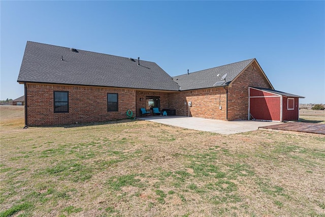 back of house featuring a patio area, brick siding, a yard, and roof with shingles