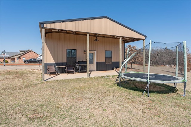 back of property featuring a patio, a trampoline, and a lawn