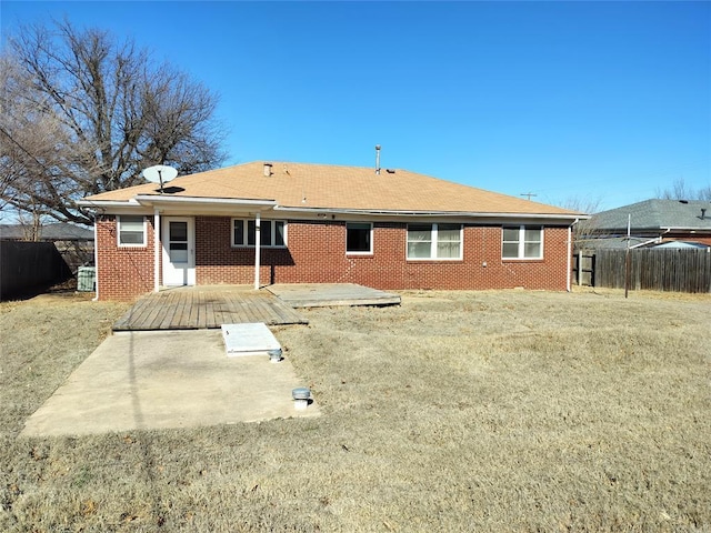 back of house featuring fence and brick siding