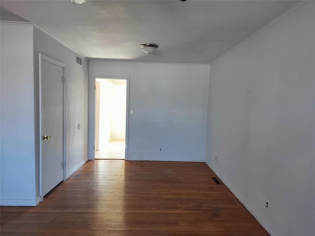 spare room with visible vents, baseboards, wood finished floors, and crown molding