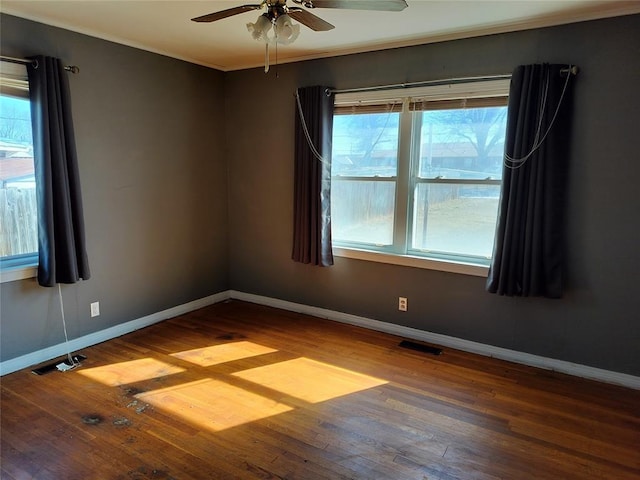 empty room with visible vents, baseboards, wood finished floors, and ornamental molding