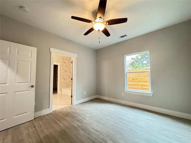 unfurnished bedroom with visible vents, ceiling fan, baseboards, wood finished floors, and ensuite bath