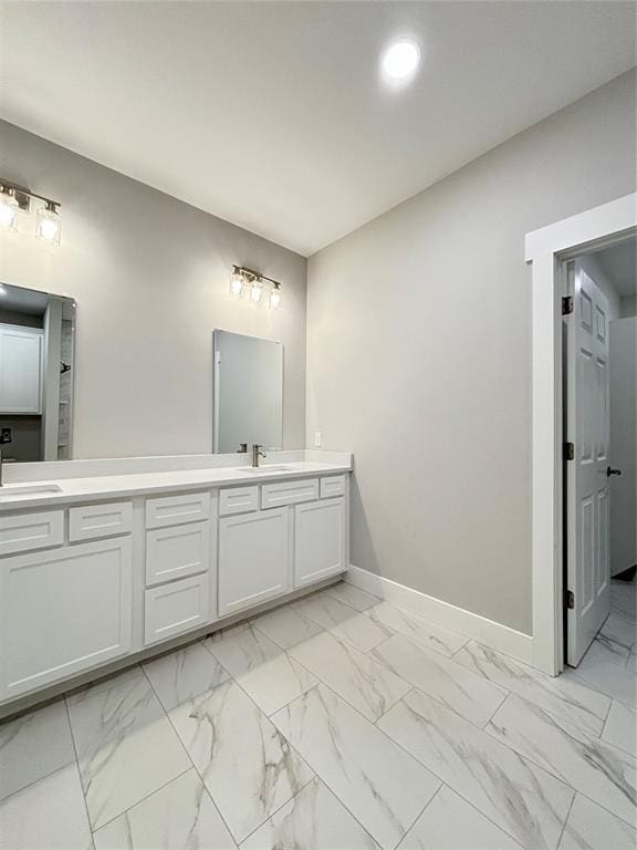 bathroom featuring a sink, baseboards, marble finish floor, and double vanity