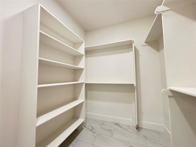 walk in closet featuring marble finish floor