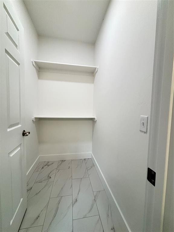 walk in closet featuring marble finish floor