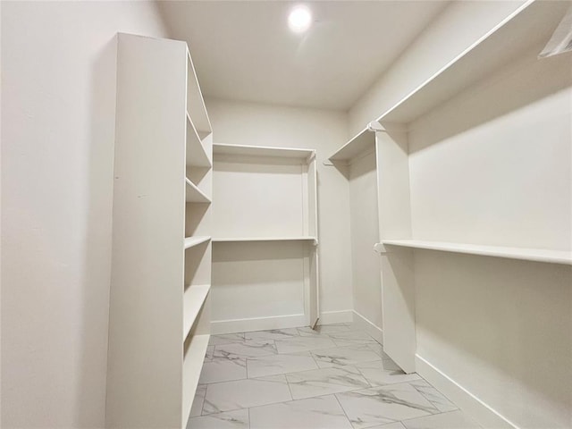 walk in closet featuring marble finish floor