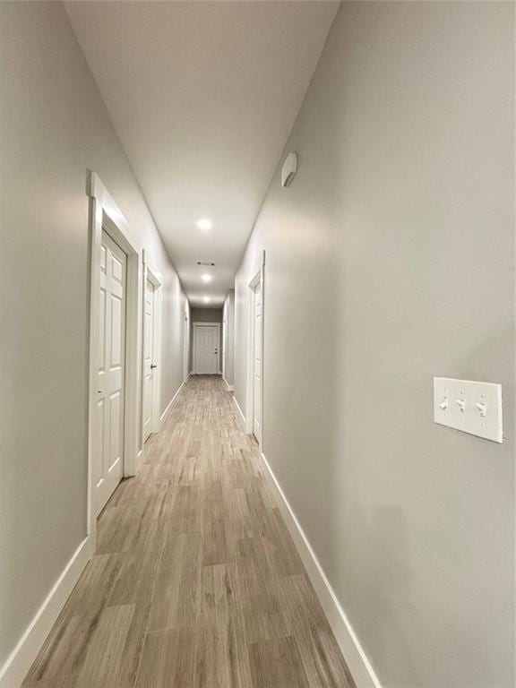 corridor featuring light wood-type flooring and baseboards